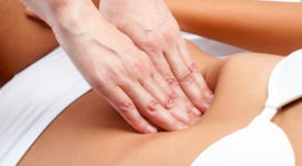 Macro close up of therapist hands doing visceral massage on female abdomen.